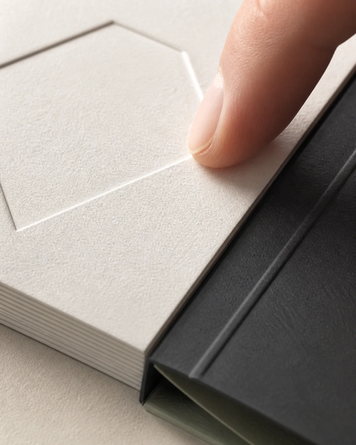 Material study of a blind deboss, cotton paper fibres and the edge of a thick ivory card.